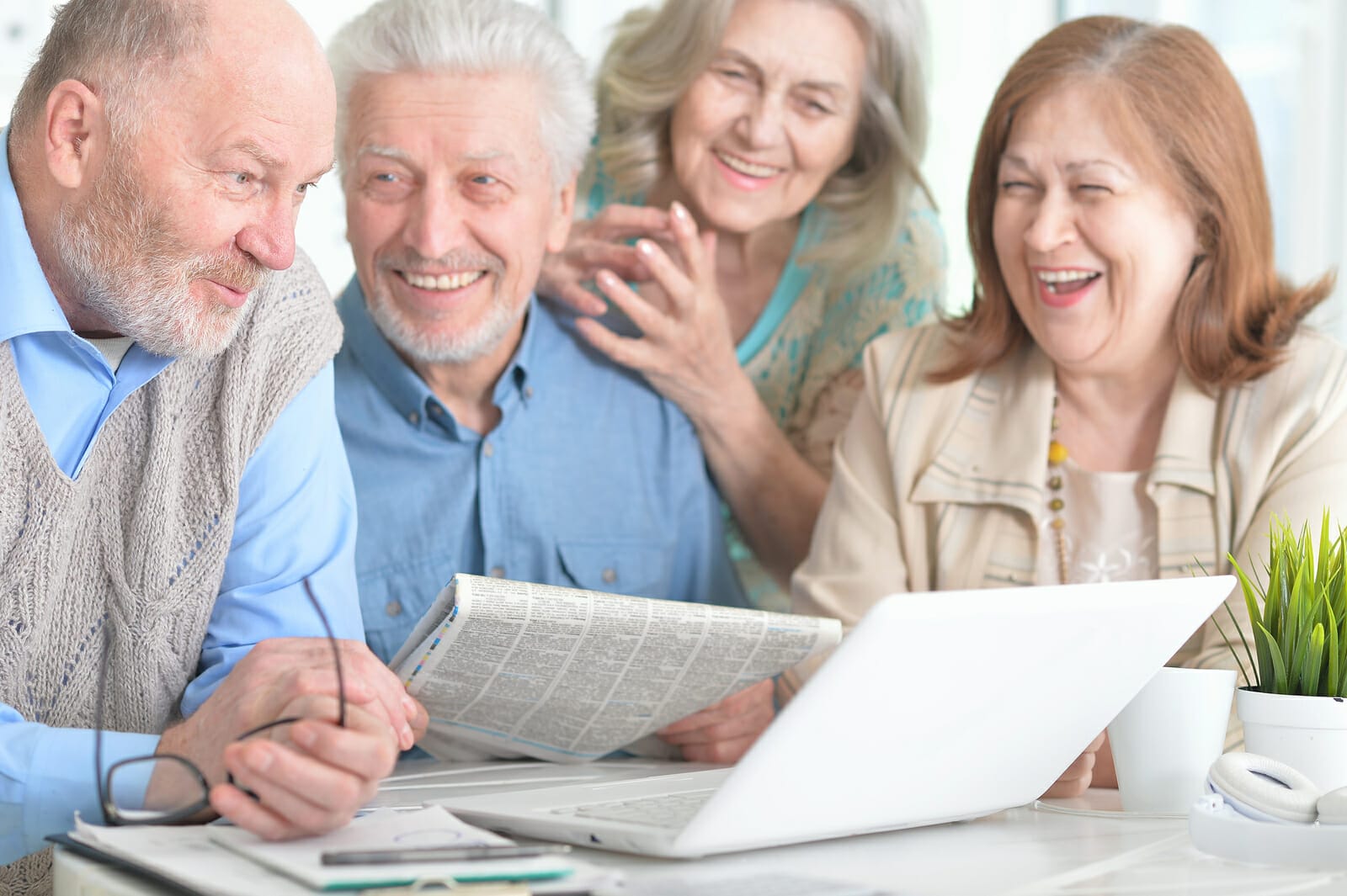 Two Senior Couples Sitting At Table And Working With Laptop